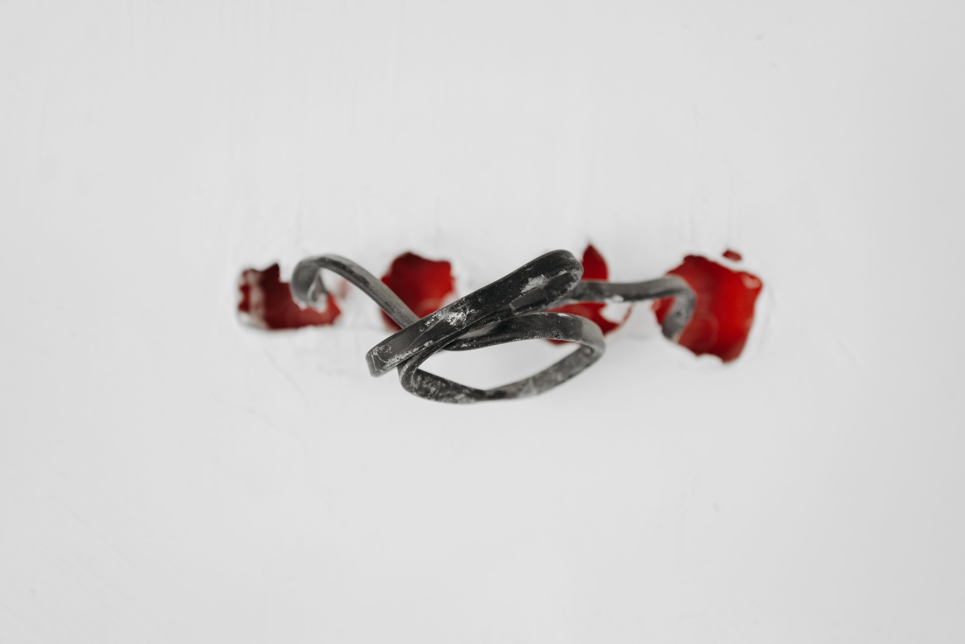 A close-up of a tangled wire protruding from red holes in a white background.