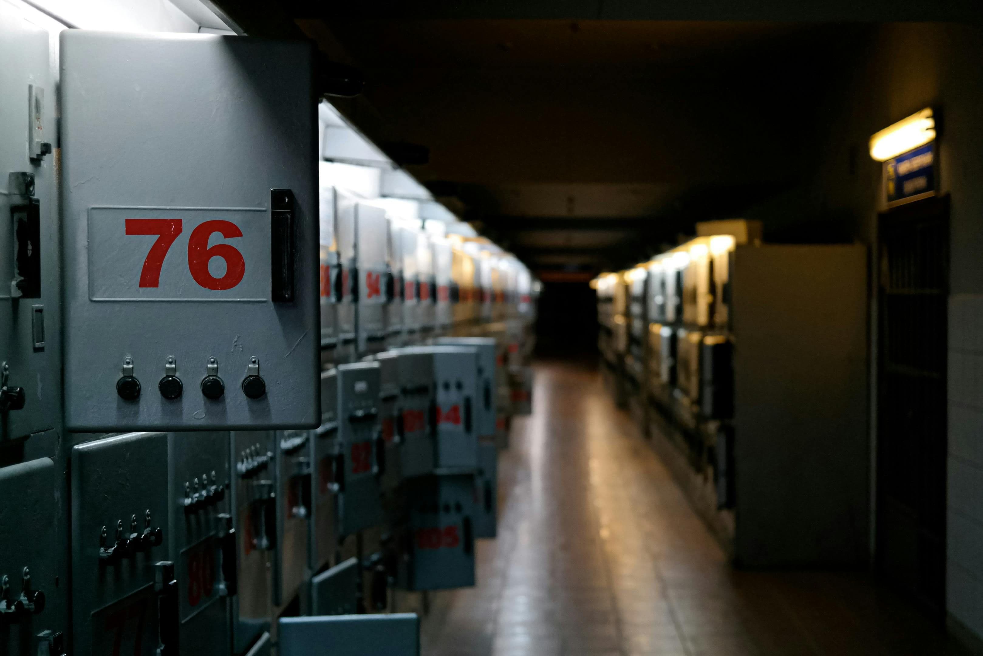 A moody shot of an industrial control room with labeled fuse boxes in dim lighting.