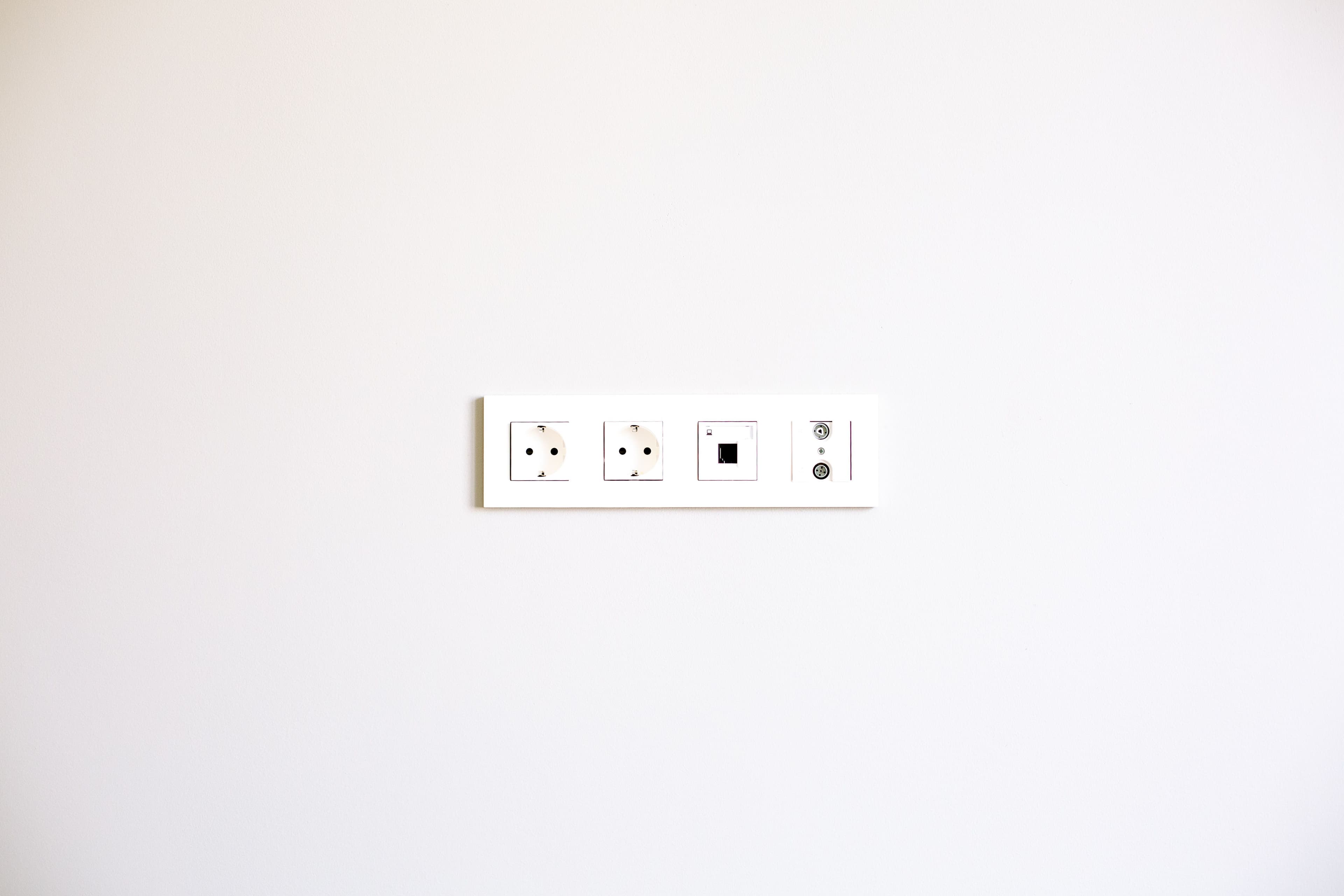 A minimalist image showcasing a modern wall outlet array on a bright white wall.