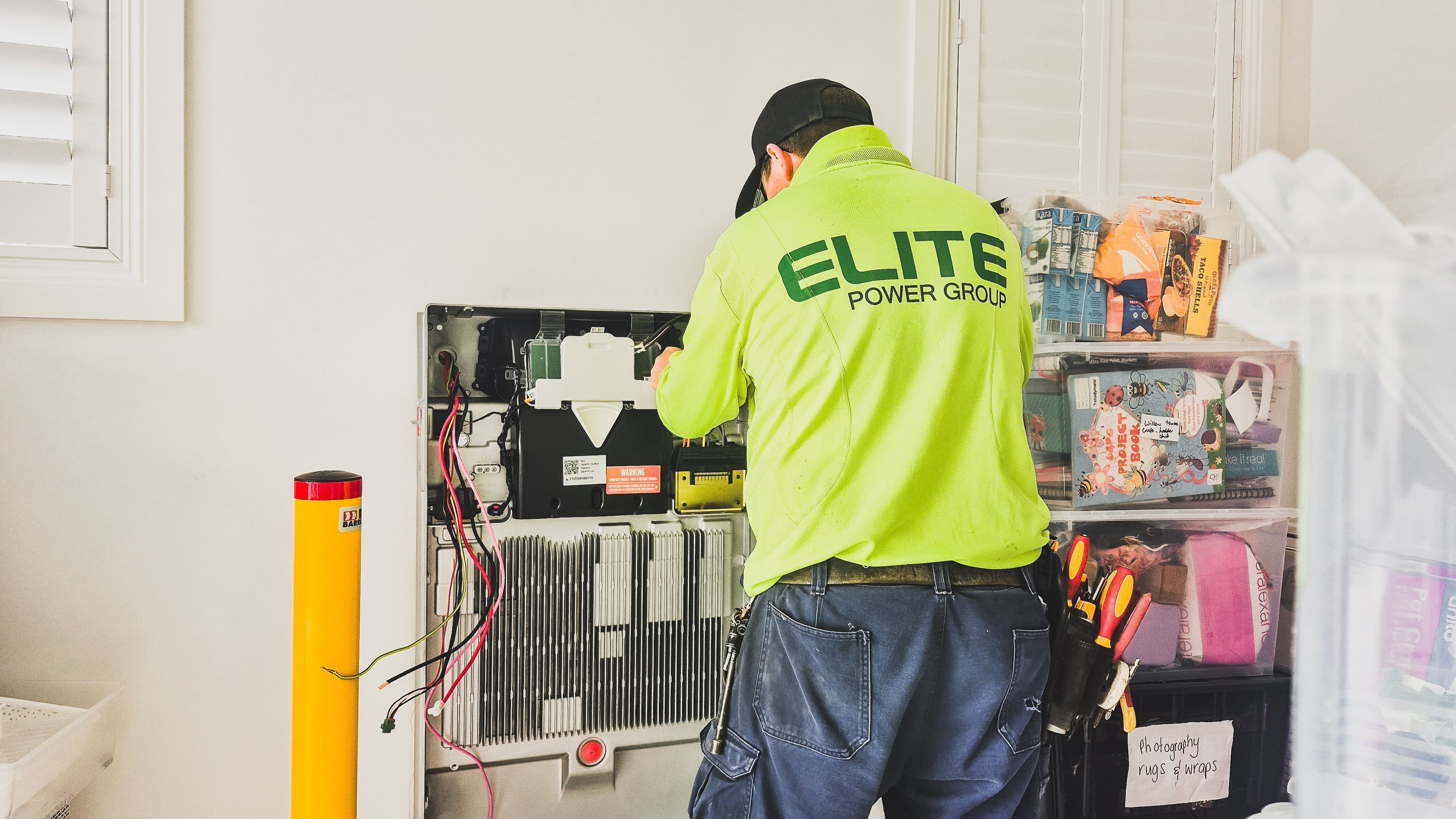 A technician from Elite Power Group installing a home battery system indoors in New South Wales, Australia.